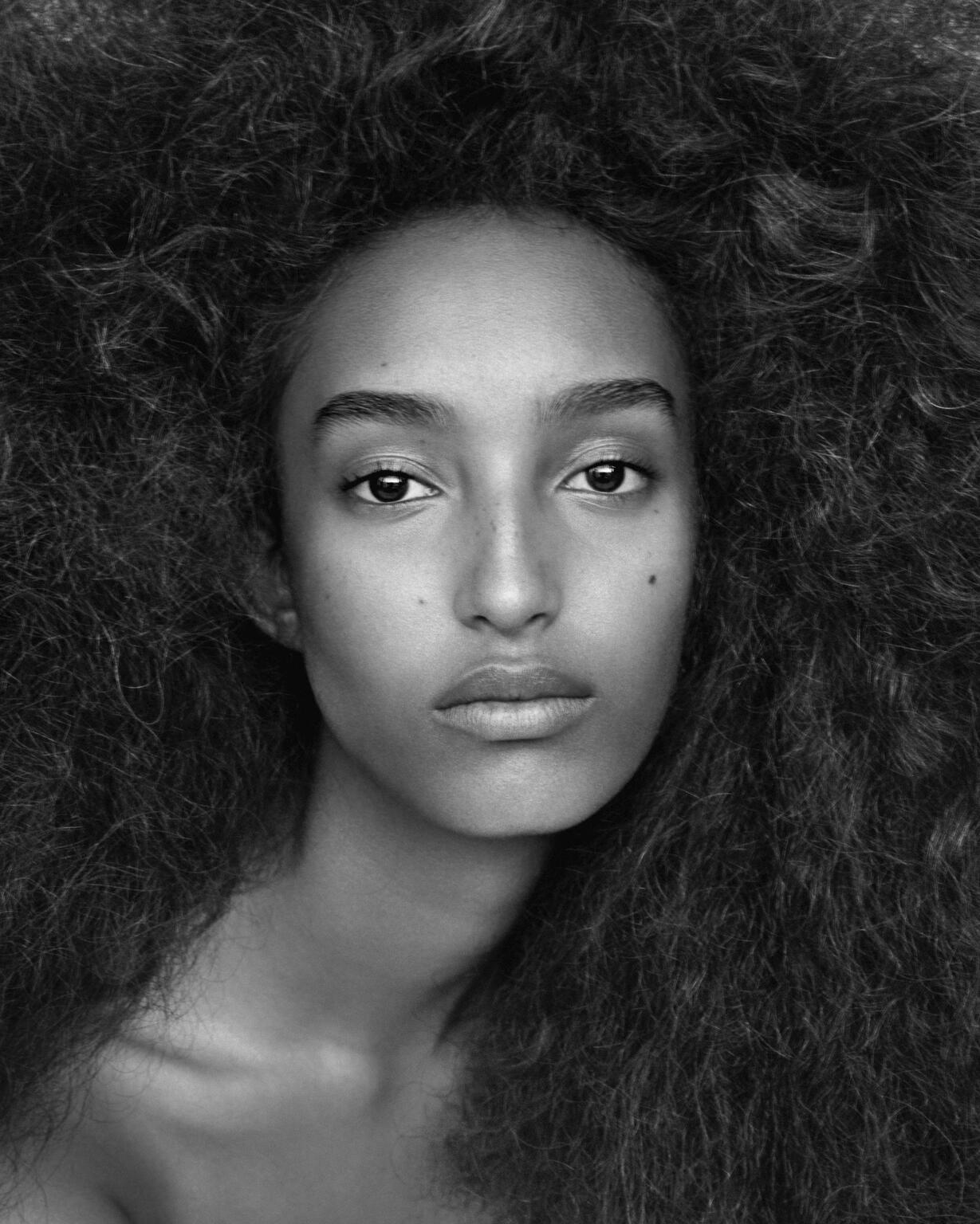 Close-up black and white portrait of a woman with voluminous textured dark hair styled by Cyndia Harvey.