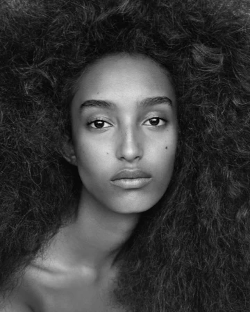 Close-up black and white portrait of a woman with voluminous textured dark hair styled by Cyndia Harvey.