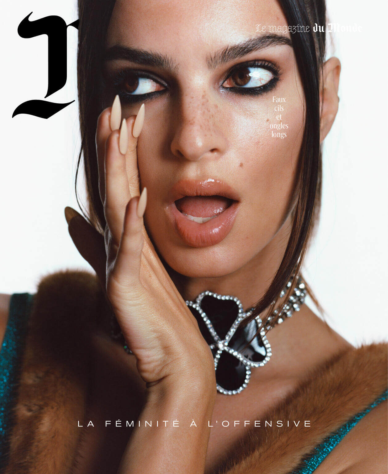 Close-up fashion magazine cover featuring a brown-haired female model with long nails, dramatic eye makeup, and an open mouth expression.