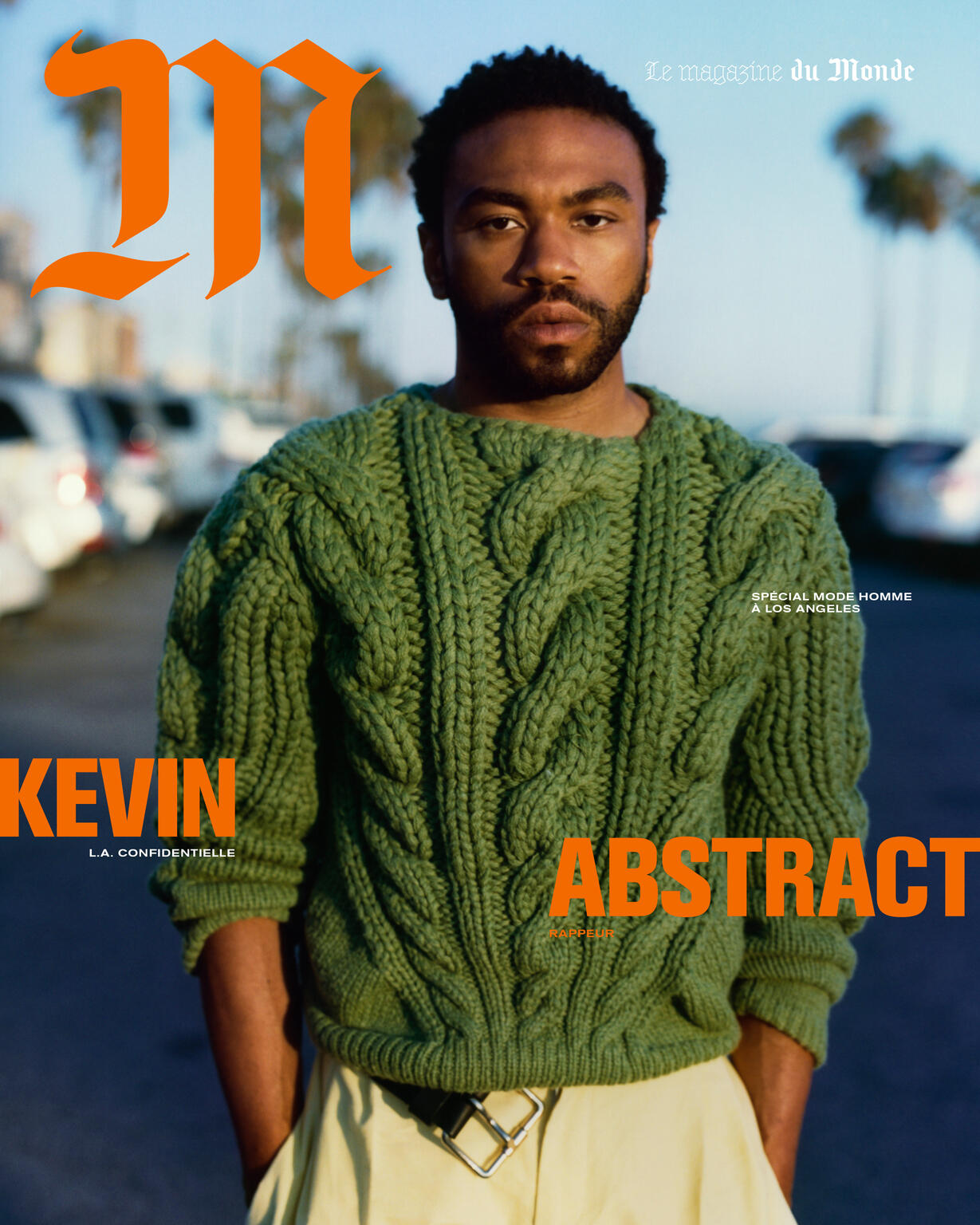 Magazine cover featuring a man with a beard wearing a green cable-knit sweater, photographed outdoors with cars in the background.
