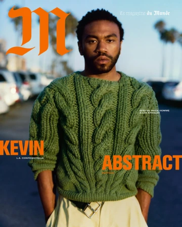 Magazine cover featuring a man with a beard wearing a green cable-knit sweater, photographed outdoors with cars in the background.