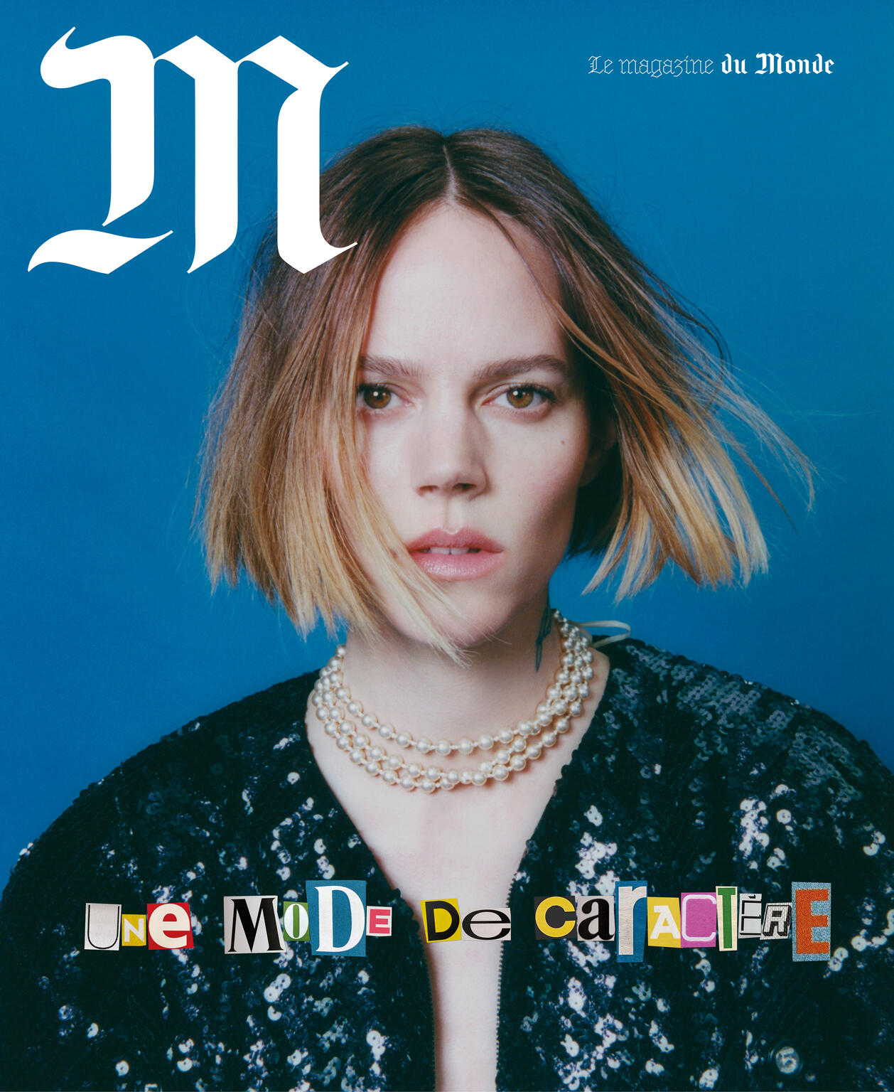 Magazine cover featuring a portrait of a woman with blonde hair, wearing a black sequin top and pearl necklace on a blue background.