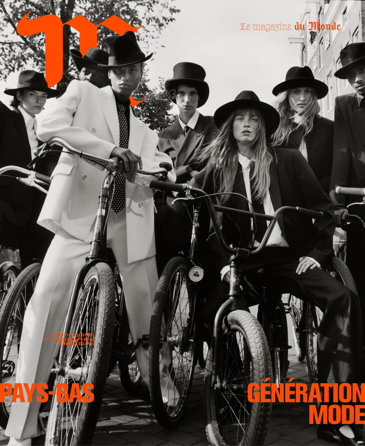 Magazine cover featuring a group of models in suits and hats posing with bicycles in an urban setting, black and white image with orange text.