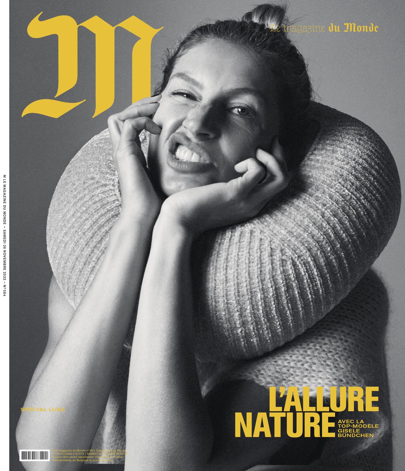 Magazine cover featuring a woman with blonde hair in a bun, making a silly face while wearing a tan-colored sweater with a high collar.