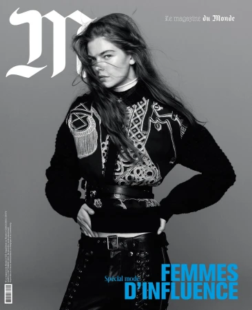 Black and white portrait of a woman in a patterned dark sweater against a grey background with magazine typography overlay