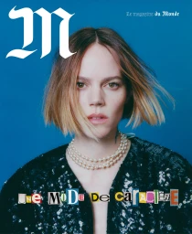 Portrait of a woman with short ombre hair wearing a pearl necklace and sequined top against a blue background.