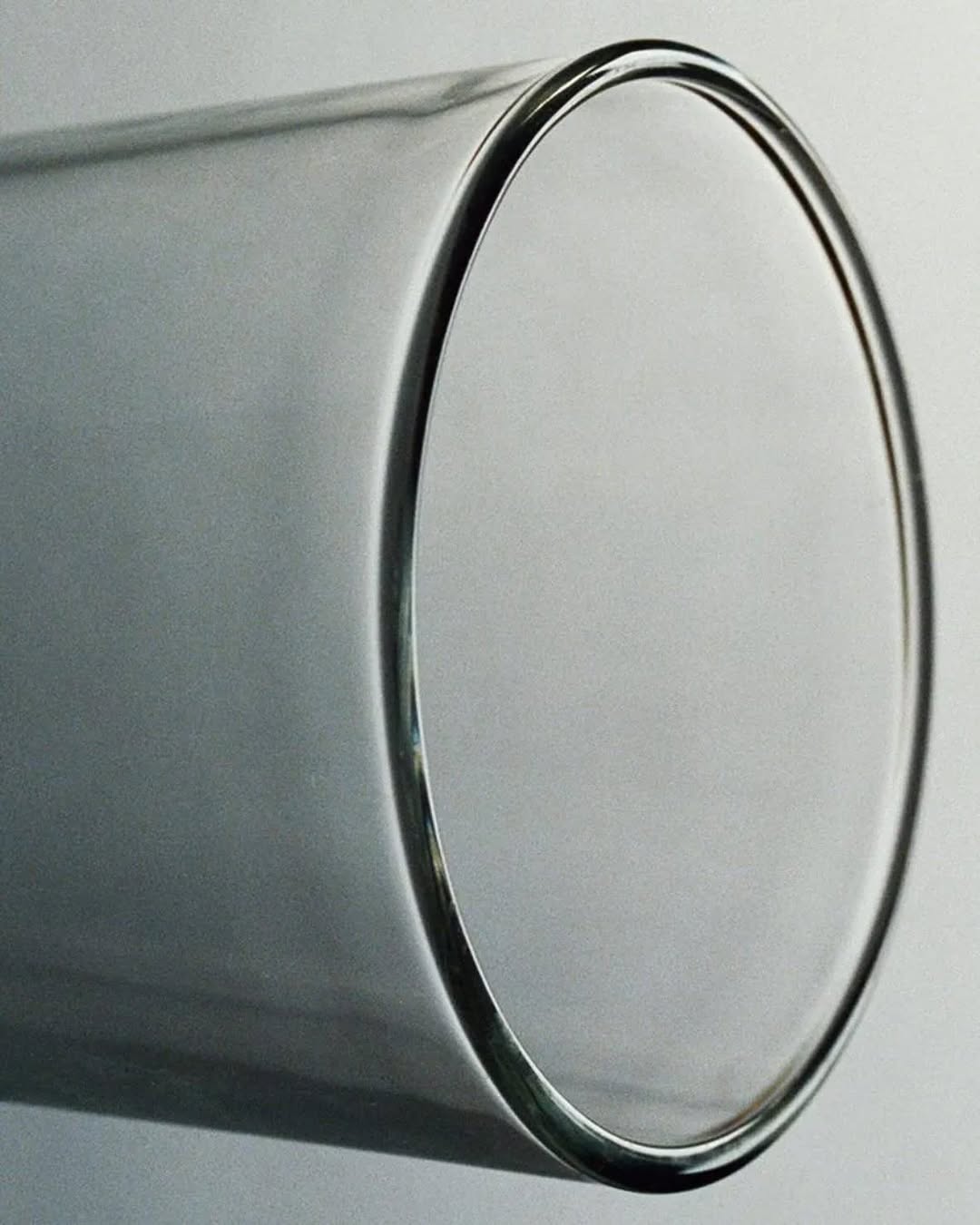 Close-up of a translucent glass cylinder showcasing subtle light play and minimalist form against a soft, neutral background. Modern, sleek design.
