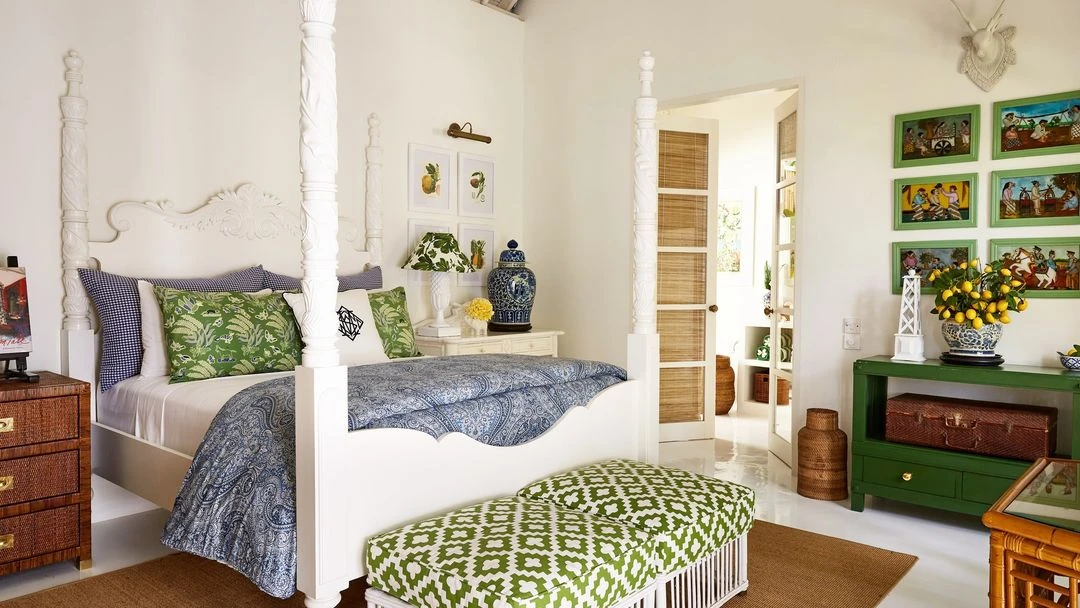 Bright, airy bedroom interior featuring a four-poster bed with patterned bedding and cushions, complemented by a green accent console table.
