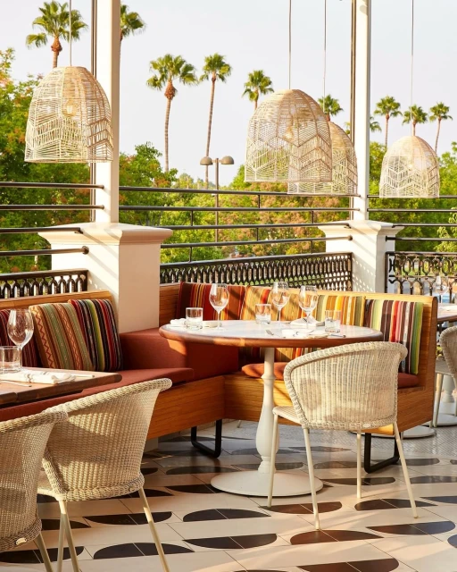 Outdoor restaurant seating area with wicker chairs, tables set for dining, and overhead lighting, capturing a warm, inviting atmosphere.