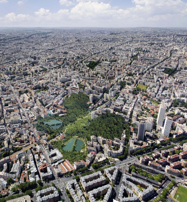 Aerial view of urban landscape featuring dense city buildings and a large green park with ponds, showcasing the cityscape.