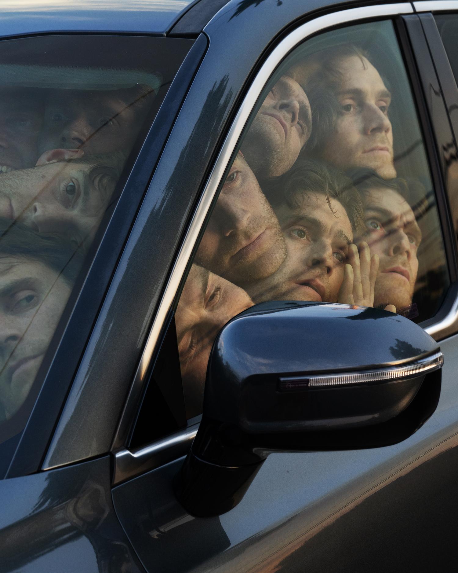 Car window reflection shows multiple faces, creating a surreal and distorted effect within the vehicle's interior and exterior.