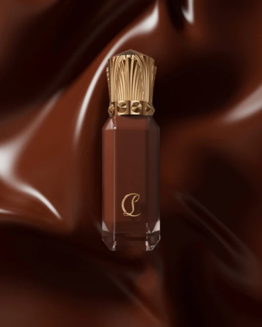 Beauty shot of a brown liquid lipstick in a clear container with a gold cap against a shiny, dark brown background.