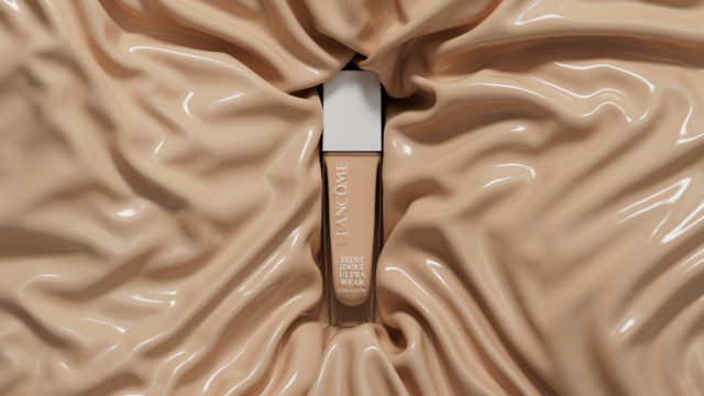 Lancôme Teint Idole Ultra Wear foundation bottle displayed against a soft, draped fabric backdrop in a close-up studio shot.