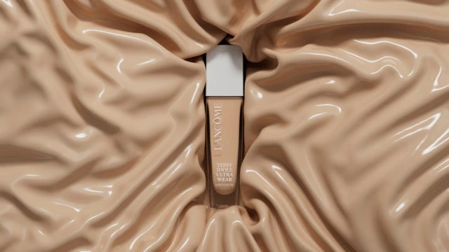 Lancôme Teint Idole Ultra Wear foundation bottle displayed against a soft, draped fabric backdrop in a close-up studio shot.