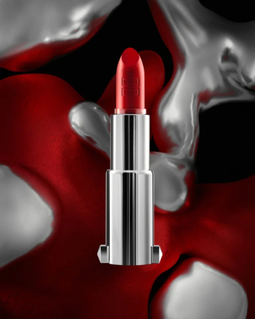 Close-up of a red lipstick tube with a silver casing against a blurred red and silver fluid-like background for beauty advertising.