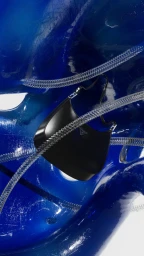 Black leather handbag suspended among glossy blue abstract sculptural forms and metallic coiled tubes