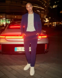 Man standing in front of a silver car with illuminated taillights at night in Sydney, photographed by Mark Bramley.