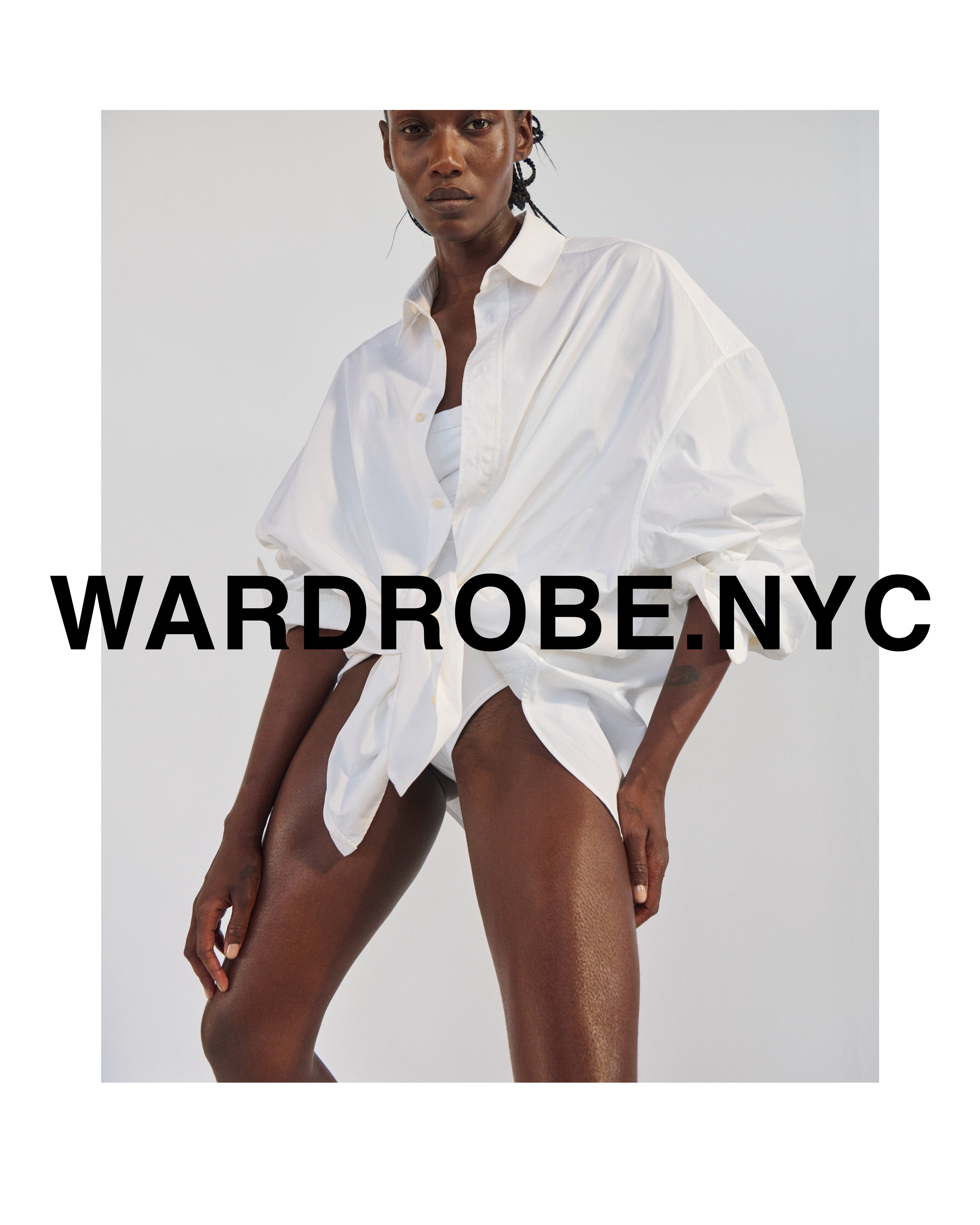 Studio shot of a tan-skinned adult woman wearing a large white collared shirt. The shirt is unbuttoned and tied at the waist.