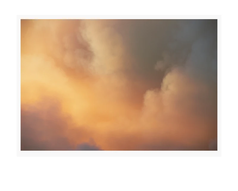 Atmospheric cloudscape featuring soft, diffused light and a gradient of warm, golden hues blending into cooler, muted grays.