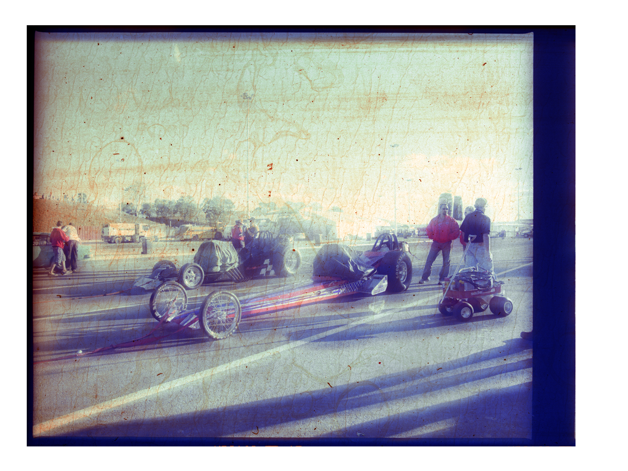 Vintage photo of race cars on a track with spectators, showing automotive sport and competition.