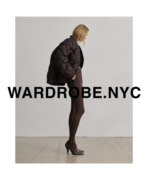 A woman poses in a studio wearing a brown quilted jacket, matching leggings, and heels. The image promotes wardrobe.nyc.