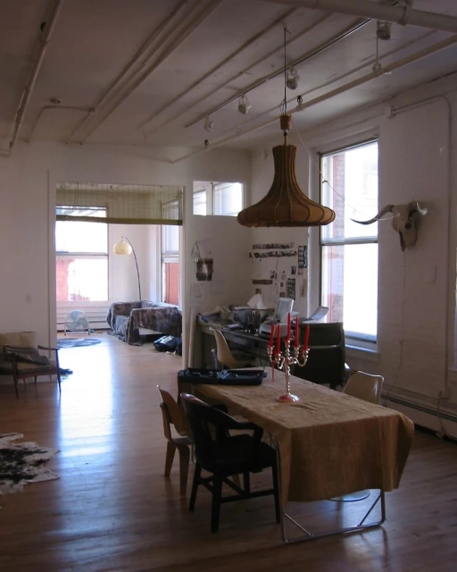 Dining room with a rustic table set, chairs, chandelier, and an animal skull mounted on the wall. Natural light floods the interior.