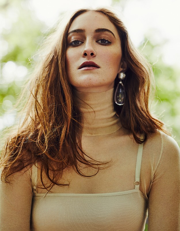 Portrait of a woman wearing a sheer tan turtleneck top and large teardrop earring with hair styled by David Keough.
