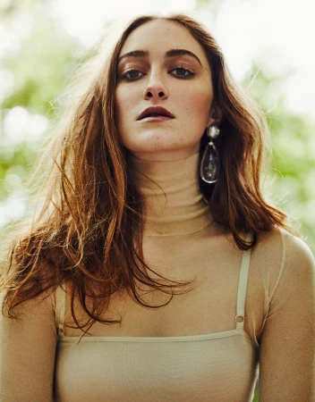 Portrait of a woman wearing a sheer tan turtleneck top and large teardrop earring with hair styled by David Keough.