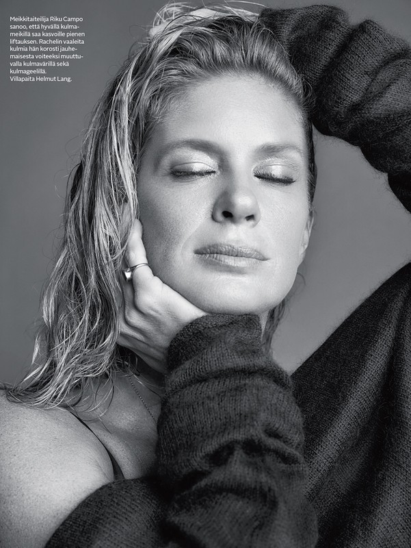 Close-up monochrome portrait of a woman with wet-look hair wearing an oversized knit sweater against a grey background.