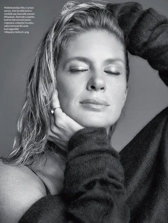 Close-up monochrome portrait of a woman with wet-look hair wearing an oversized knit sweater against a grey background.