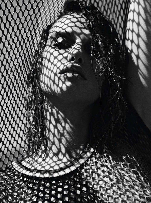 Monochrome portrait of a woman with wet hair under heavy patterned shadows from a mesh screen
