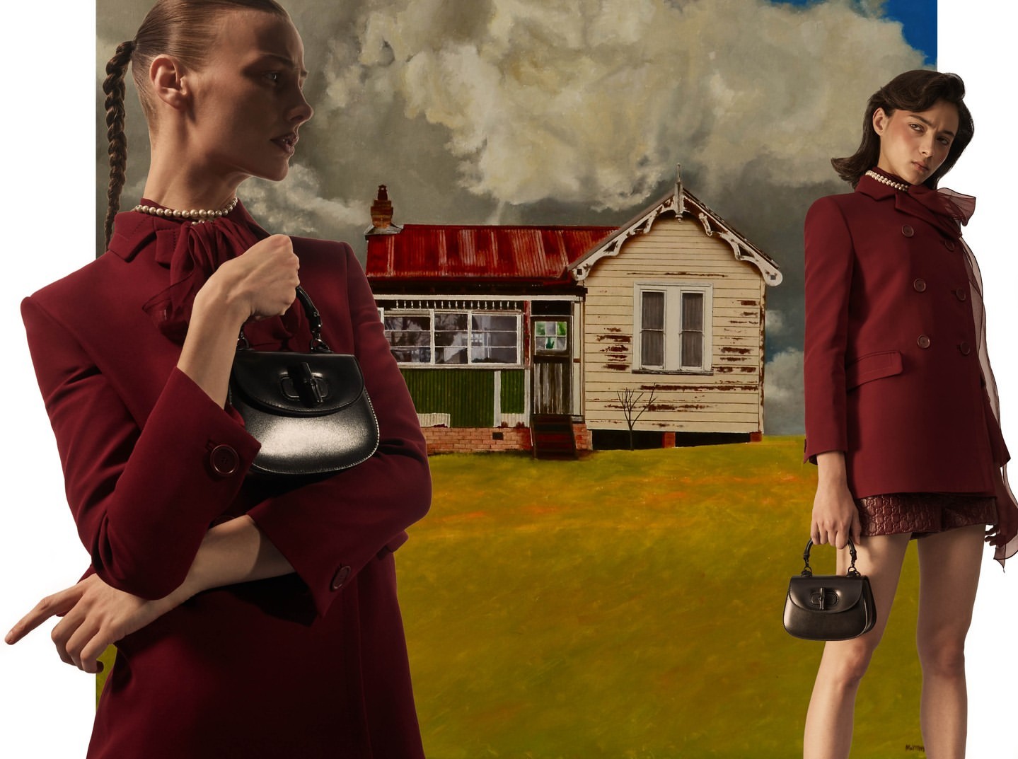 Two women in jackets hold purses, posing in front of a painting of a rural house on a yellow hill under a cloudy sky in a fashion editorial.