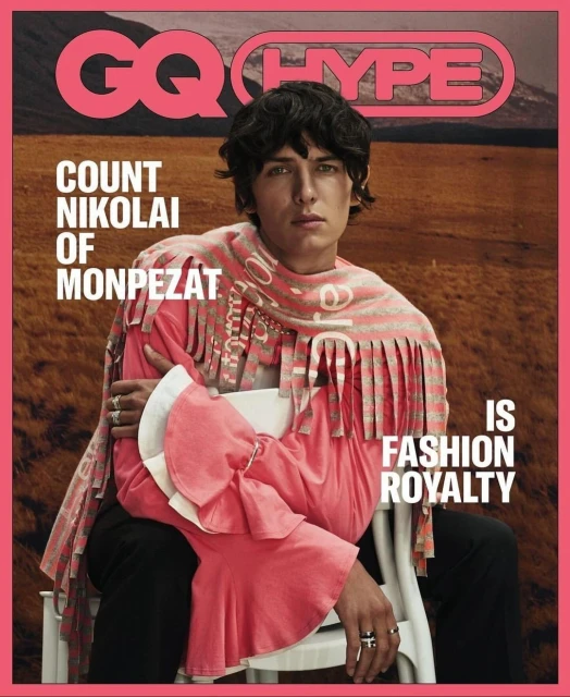 Magazine cover featuring a portrait of a young adult male wearing a pink top and patterned scarf, seated against an outdoor background.