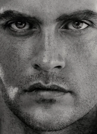 Close-up monochrome portrait of a man's face focusing intently on his eyes and textured skin details