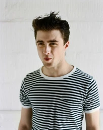 Portrait of a young man wearing a black and white striped t-shirt against a white background.