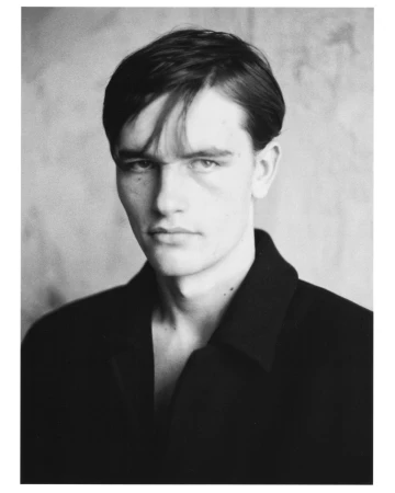 Portrait of a man wearing a dark jacket against a textured neutral background, styled by Alberto Vegue