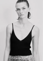 Model in a black ribbed tank top with dark winged eyeliner against a plain light background