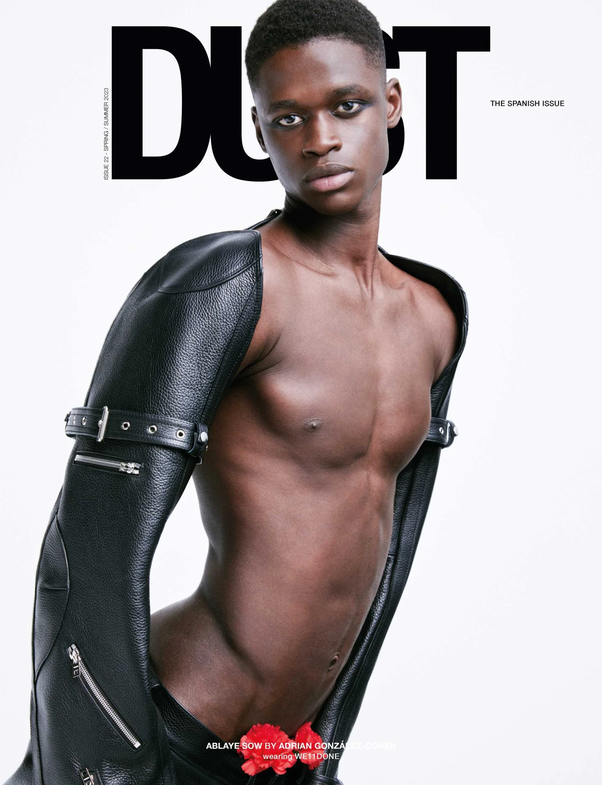 Magazine cover featuring a Black man with a muscular build, wearing black leather sleeves, posing against a bright white backdrop. 