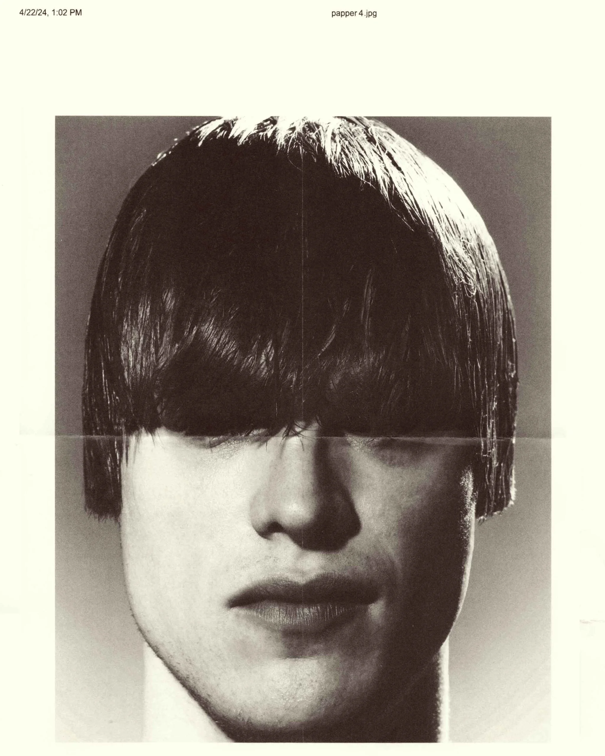 Close-up monochrome portrait of a person with a bowl cut obscuring their eyes against a neutral background.