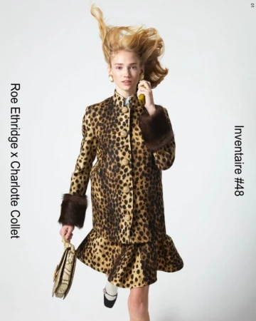 A woman in a vintage animal print skirt suit and Mary Janes holds a yellow object and a purse against a white background.