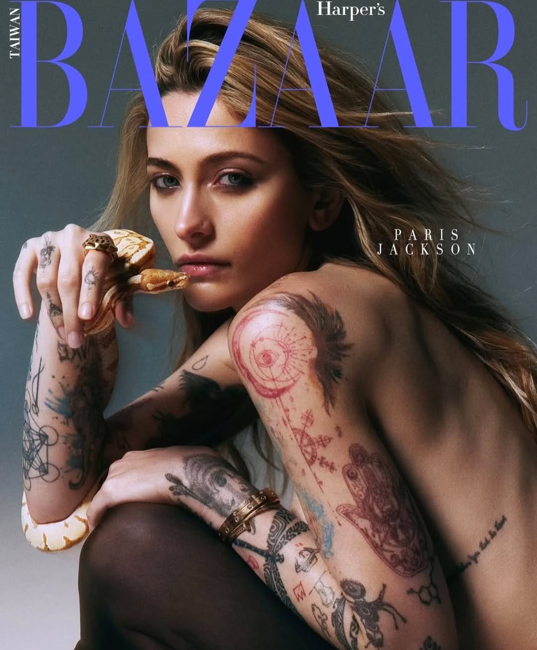 Paris Jackson, partially bare-shouldered, holds a yellow and white snake, against a gray background, on the cover of Taiwan Bazaar.
