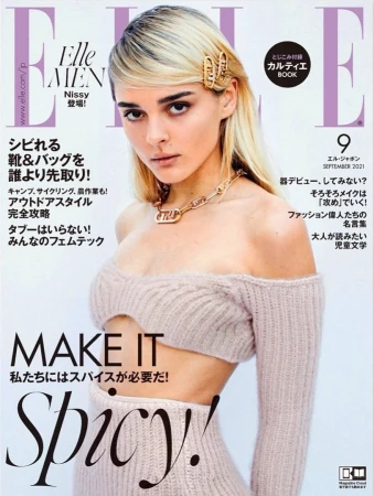Magazine cover featuring a woman wearing an off-the-shoulder knit top with gold hair clips and chunky chain necklace.