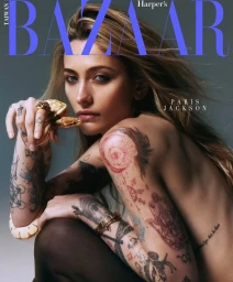Paris Jackson with extensive tattoos holding a light-colored snake for a magazine cover portrait.