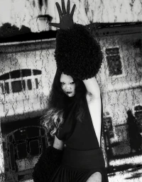 Model in black avant-garde outfit with textured hand-raised glove and distressed background, styled by Victoire Simonney