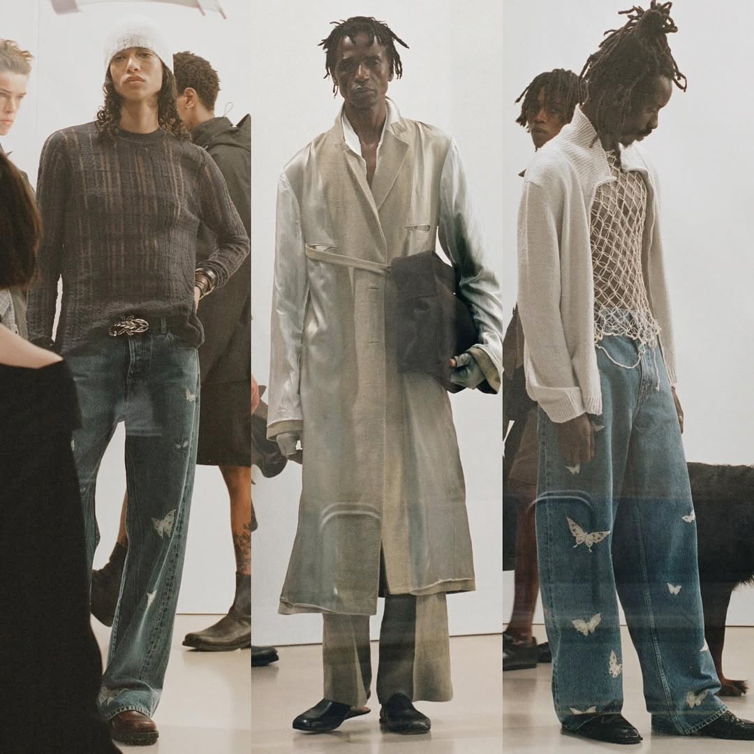 Runway fashion shot featuring three models in streetwear-inspired outfits, showcasing denim jeans and neutral-tone layering against a clean backdrop.