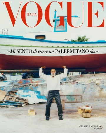 An elderly man holding a large fishing boat above his head against a stone wall and coastal background for a Vogue Italia cover