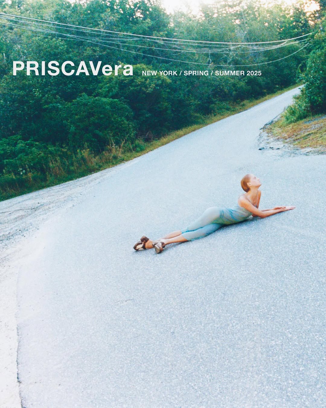 Fashion editorial featuring a model lying on a road surrounded by trees, showcasing apparel from Priscavera's New York Spring/Summer 2025 collection.