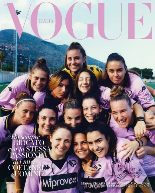 Vogue Italia cover featuring a group of female soccer players smiling in pink jerseys against a backdrop of green fields and distant mountains.