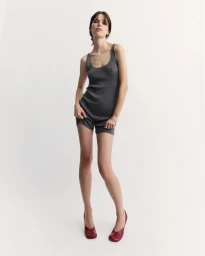 Model wearing a grey ribbed tank top and matching shorts with red shoes against a white background