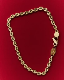 Gold chain necklace displayed on a rich red velvet textured surface